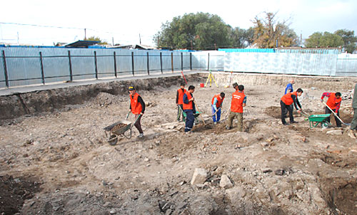 Рабочие снимают верхний слой почвы на месте раскопок